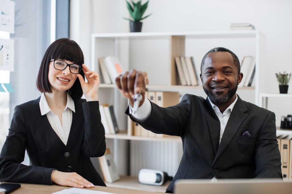 Multiracial estate agents holding house key in office